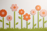 Eight orange and pink flowers with green leaves and stems made from sound dampening felt material against a white background