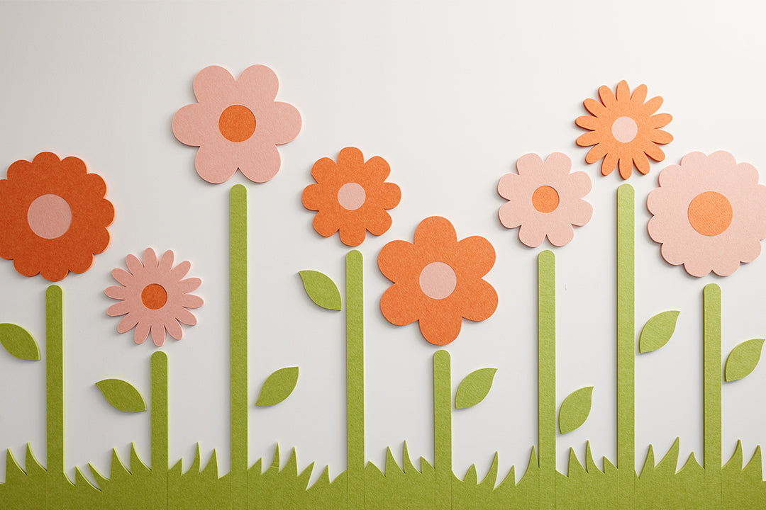 Eight orange and pink flowers with green leaves and stems made from sound dampening felt material against a white background