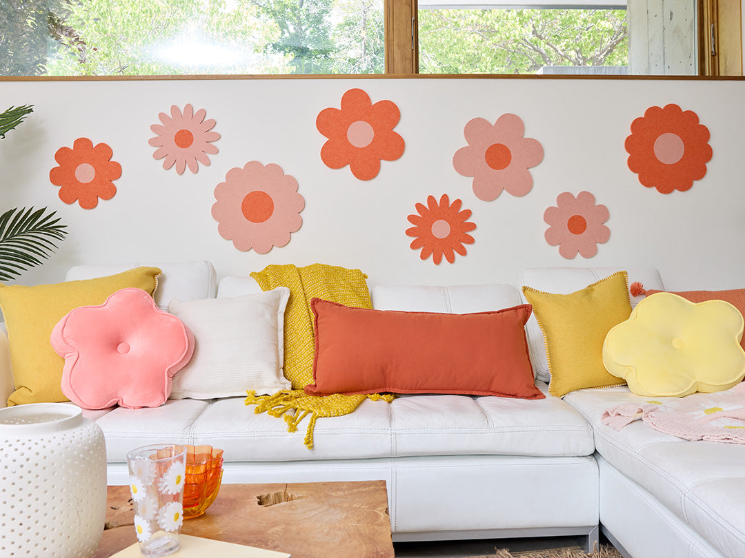 White sofa with colorful cushions and flower decals on a wall