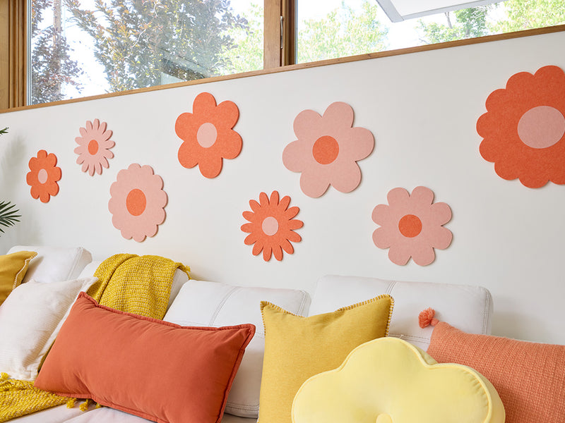 White sofa with colorful cushions and flower decals on a wall
