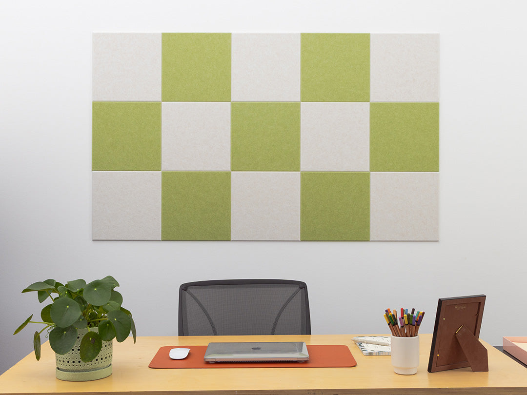 Checkered green and white wall panel above a desk with office supplies.