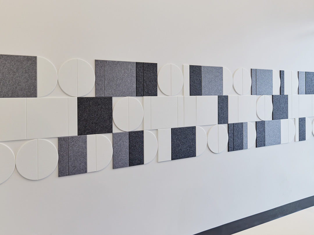 Felt Right felt tiles in shades of black and white creating a geometric pattern along a white wall.