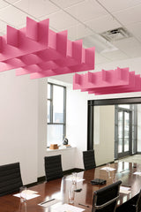 Pink 3D cloud-shaped acoustic baffles suspended from ceiling in office conference room with grid pattern layout.
