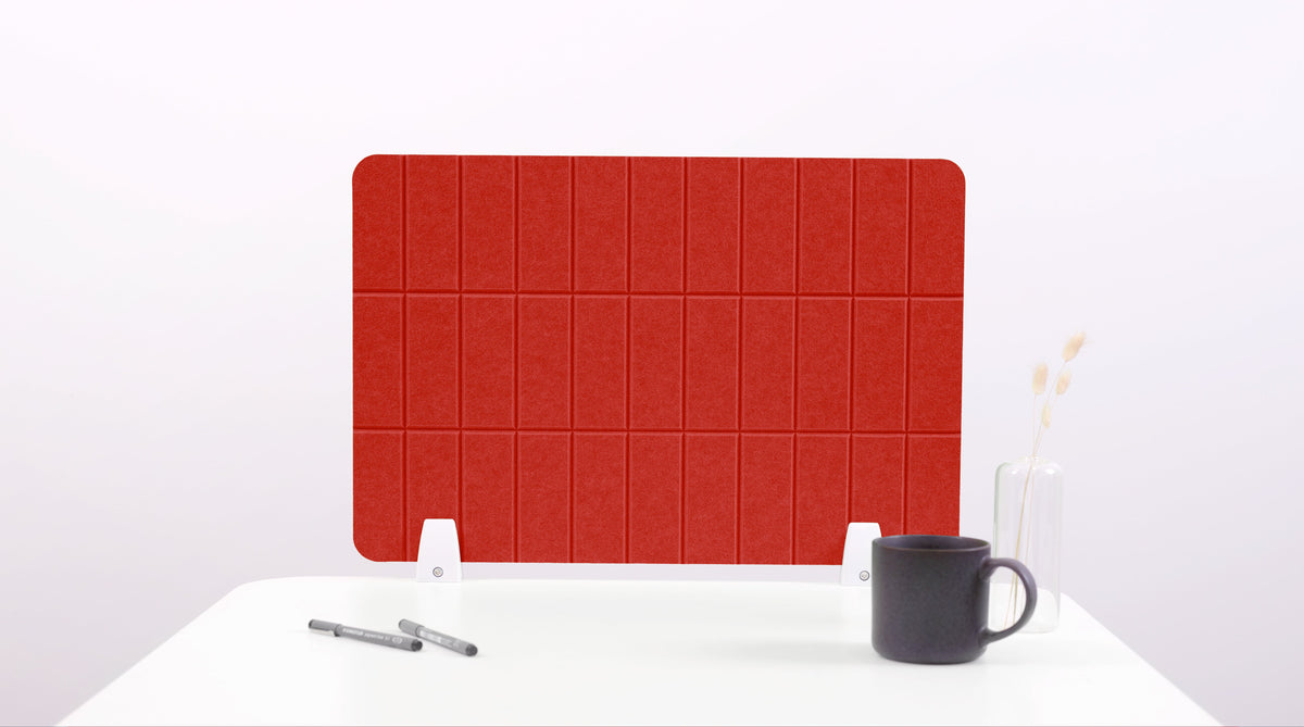 Red rectangular desk divider with grid lines, on a white surface with a black mug and pen.