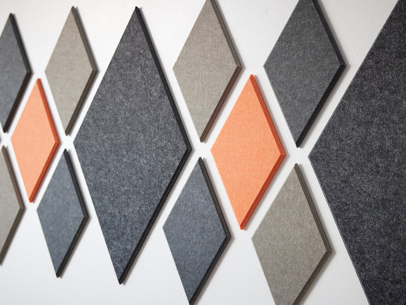 A Felt Right wall art design in grey and orange felt diamonds on a white wall 
