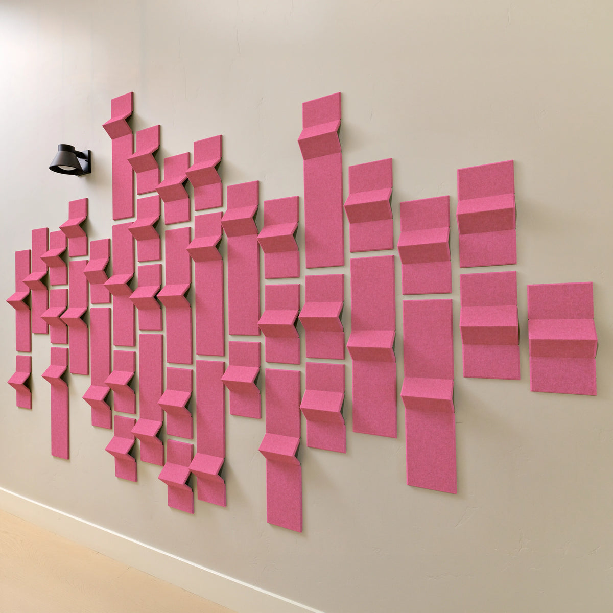 Hot pink acoustic felt tiles with points of dimension along a wall