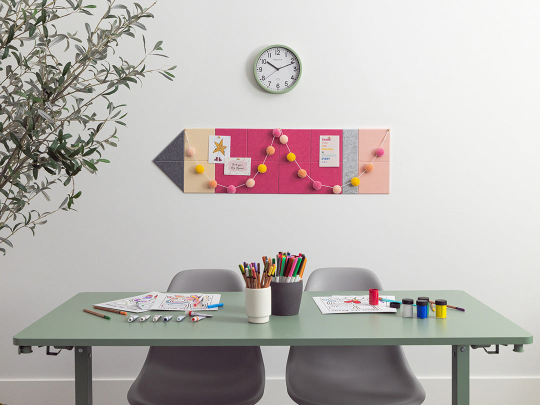 Desk with stationery items, a clock on the wall, and a decorative board with colorful pins.