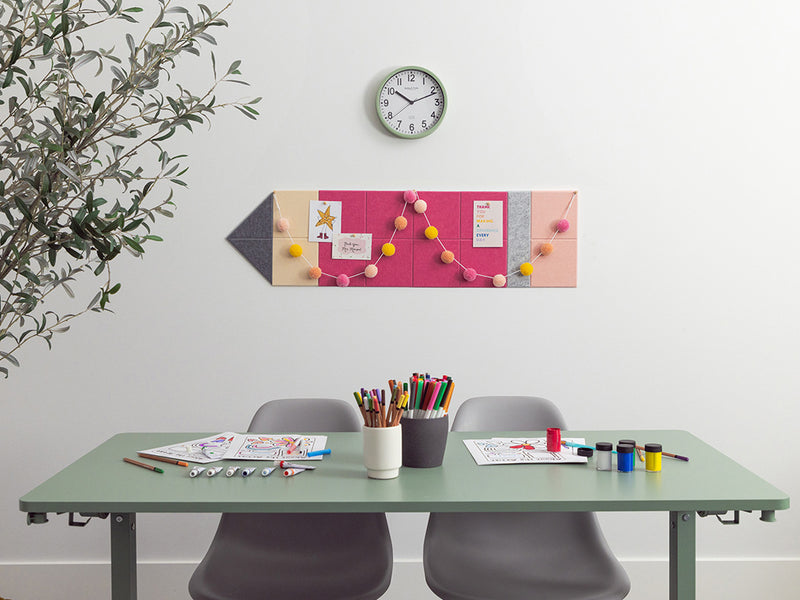 Desk with stationery items, a clock on the wall, and a decorative board with colorful pins.