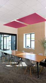 Two pink square acoustic baffles suspended from ceiling above wooden conference table.
