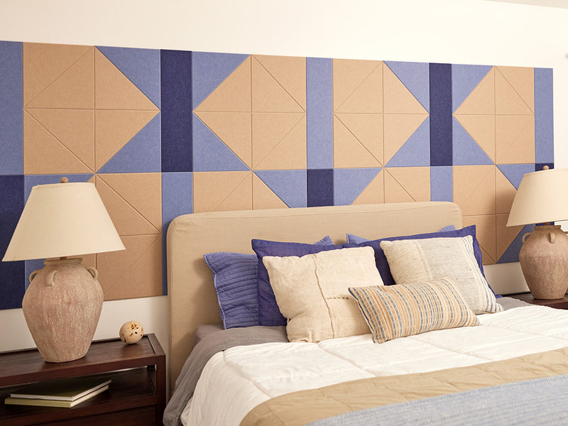 A Felt Right wall design in cream and blue behind a bed and two side tables and matching lamps