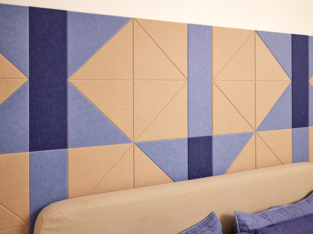 A Felt Right wall design in cream and blue felt tiles behind a bed  