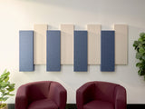 Four alternating blue and cream rectangular acoustic panels mounted on white wall above two burgundy armchairs.