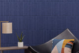 Modern interior with a blue textured acoustic wall, black chair, and decorative pillow.
