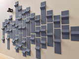 Three-dimensional gray tiles arranged in a staggered wall installation showing varying depths and light angles.