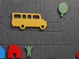 Toy bus and figures on a gray play mat with road markings