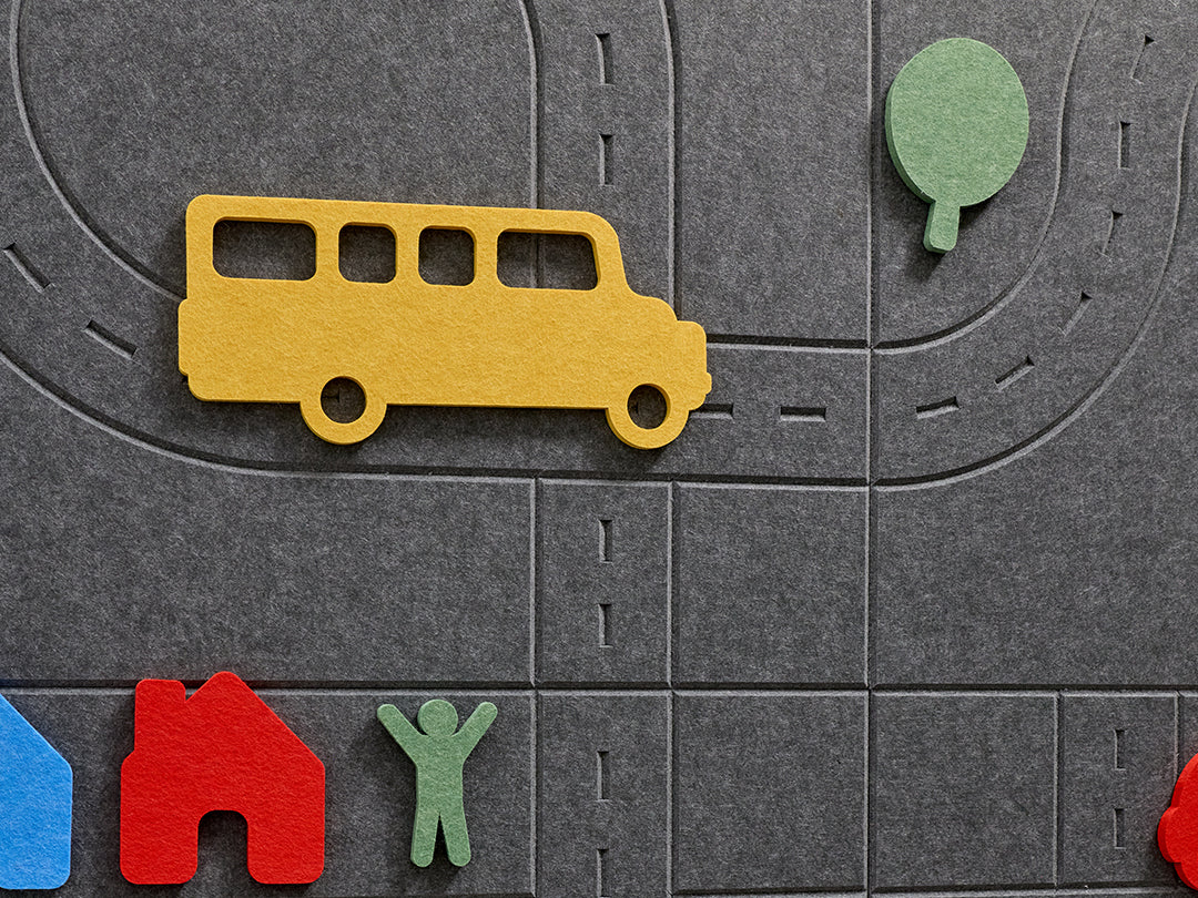 Toy bus and figures on a gray play mat with road markings
