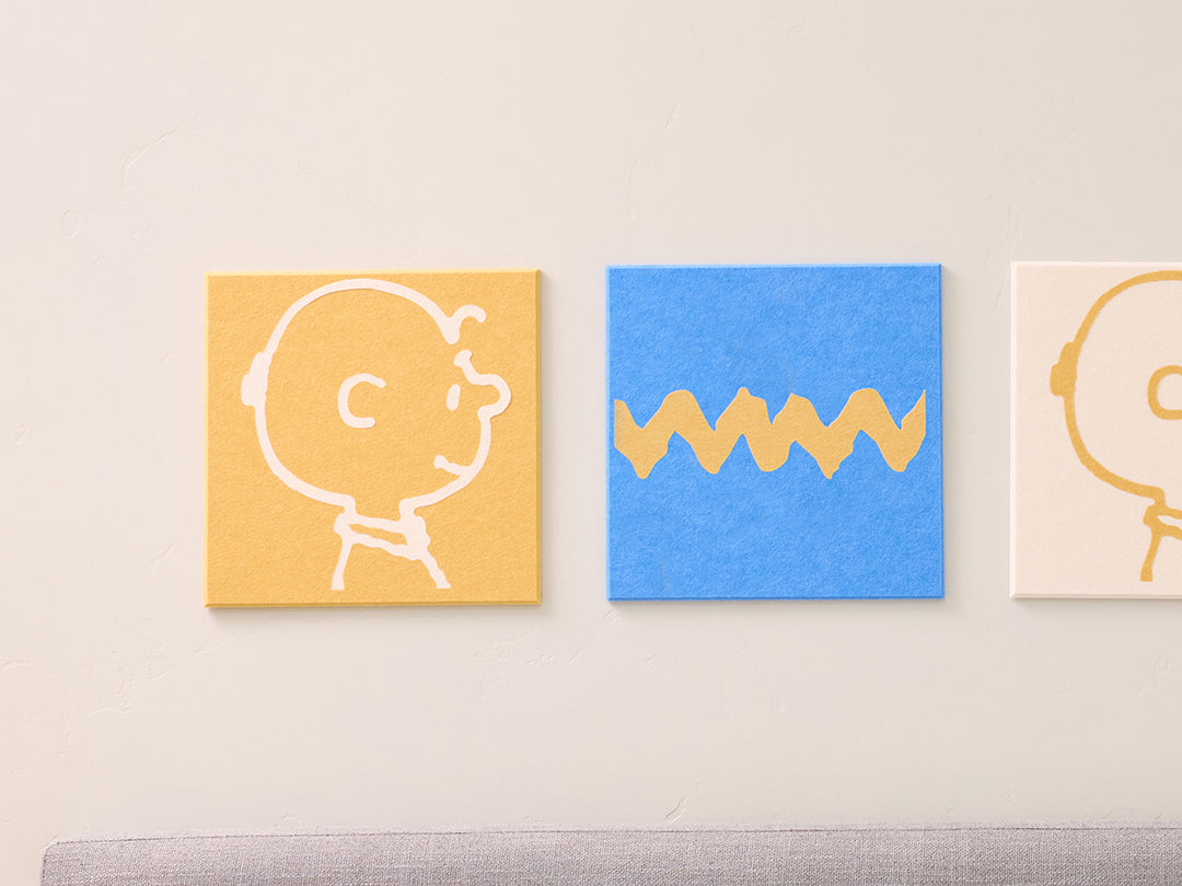 close up of Charlie felt tiles and zig zag felt tiles on a wall above a bed with decorative pillows.