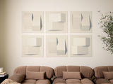 Six beige tiles with three-dimensional geometric shapes and shadows arranged in a grid on a wall above a brown sofa.