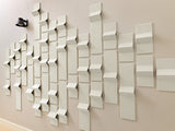 White three-dimensional tiles mounted on wall in staggered pattern with varying heights and angles.