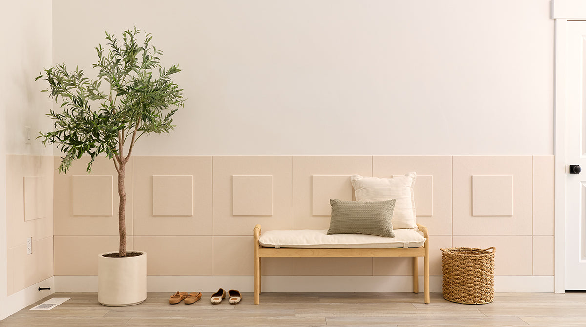 Wainscoting in a nook with a plant, bench, and shoes on a wooden floor.