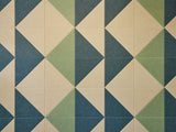 A Felt Right wall art design in shades of green and cream triangles tiles covering a wall.