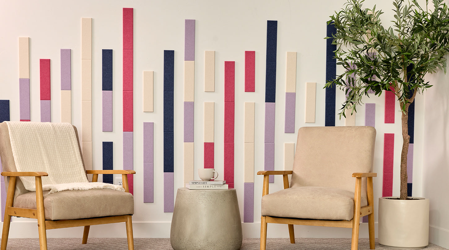 Two beige armchairs in a room with a decorative wall featuring vertical color acoustic tiles.