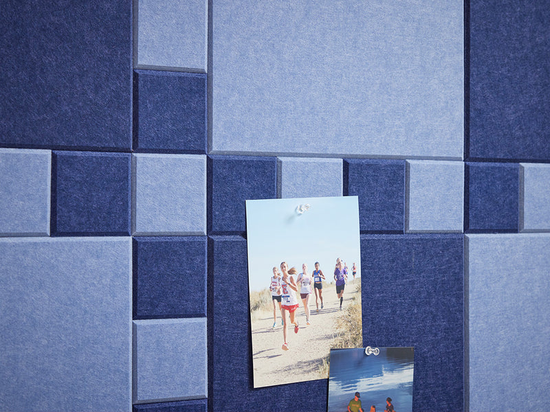 A Felt Right wall art design in shades of blue felt squares making a puzzle like pattern and two photos pinned to the tiles