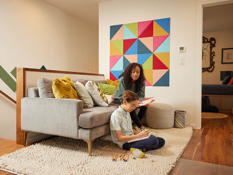 Woman and child in a living room with a colorful geometric wall art piece.