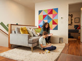 Woman and child in a living room with a colorful geometric wall art piece.