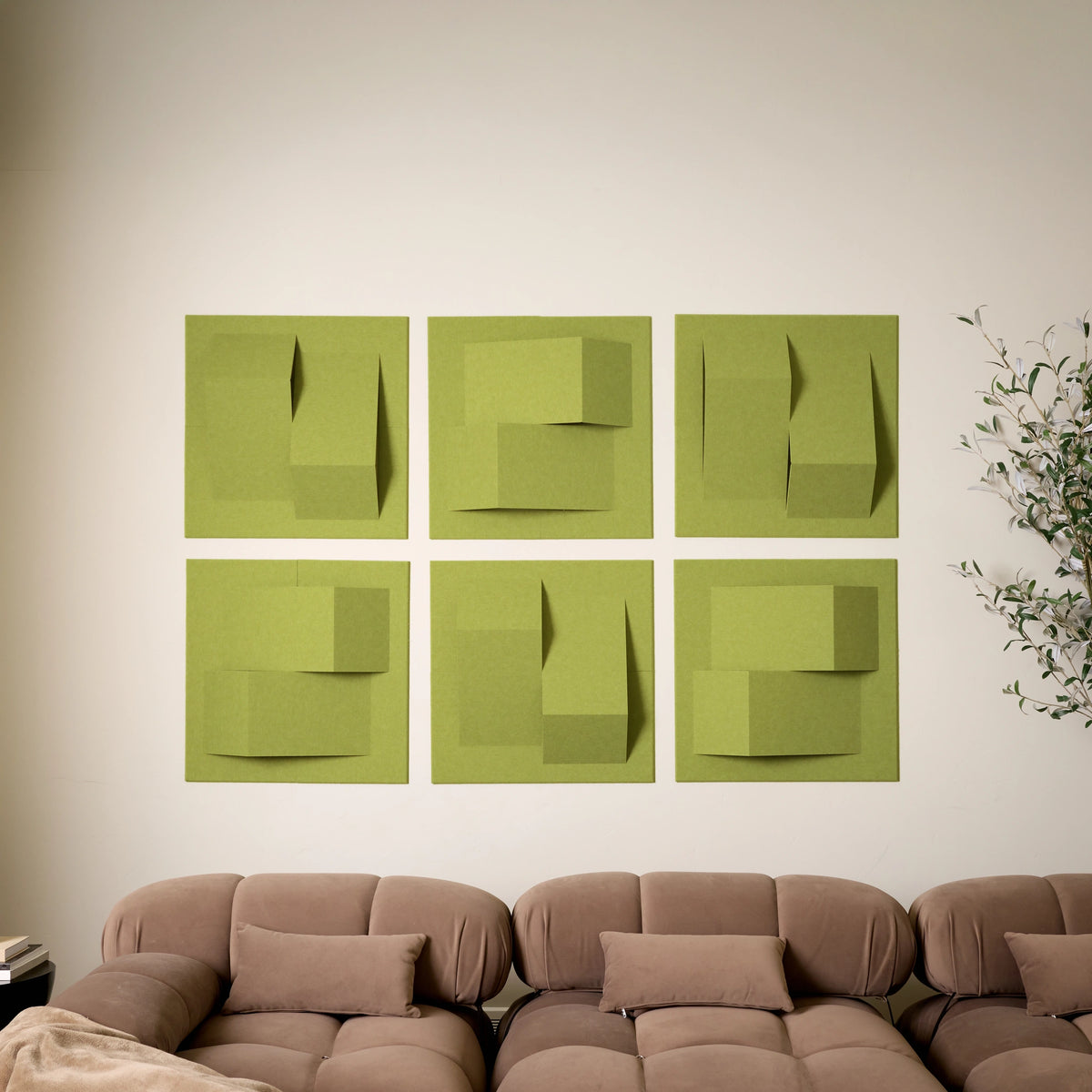 Light green acoustic felt tiles with points of design on a white wall above a couch