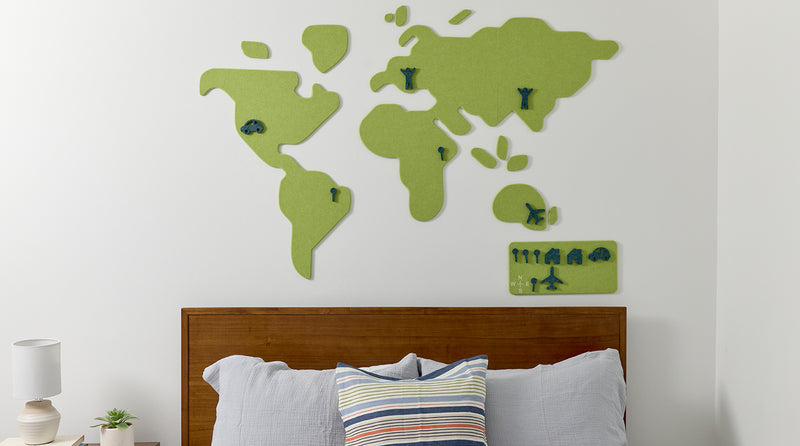 World map wall panel on a white wall above a bed with pillows.