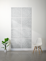 A modern wall art piece made of nine square panels arranged in a 3x3 grid, featuring a textured silver and white chevron pattern. The panels are mounted on a white wall in a minimalist room setting with a small green potted plant on the left and a white molded chair with wooden legs on the right.