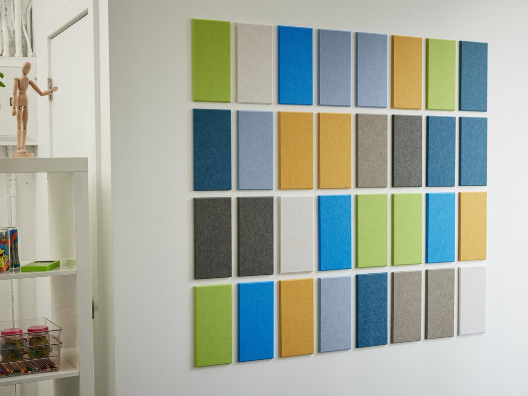 A Felt Right Wall Art design in shades of blue green grey white and yellow felt tiles next to a shelf.