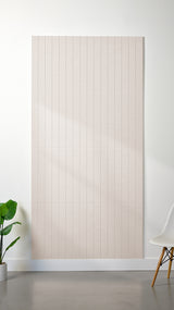 Heathered grey Felt Right 4’ x 8’ PET felt panel with straight vertical lines engraved into the material against a white wall. A plant and chair are in the foreground.