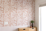 Wall with floral patterned wallpaper next to a wooden cabinet with a vase and plant.