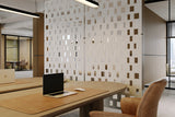 Modern office setting with a desk, laptop, and chair in front of a decorative acoustic room divider.