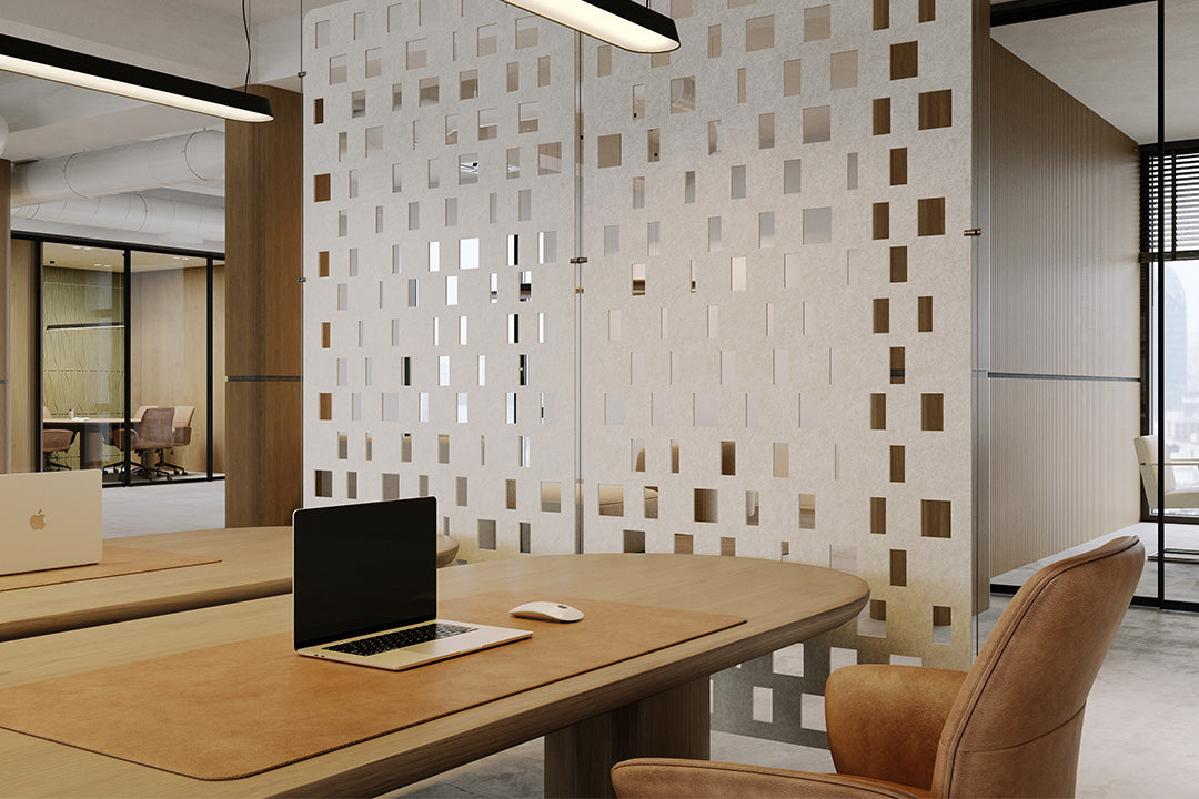 Modern office setting with a desk, laptop, and chair in front of a decorative acoustic room divider.