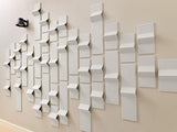 White three-dimensional tiles mounted on beige wall in staggered pattern with varying depths and angles.