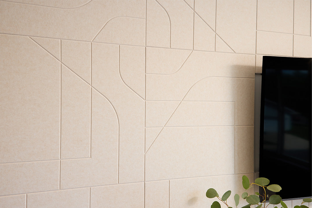 Beige acoustic wall panels with a television and plant in the corner