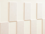 Felt Right wall art design using cream felt tiles and negative space to create a pattern going around the wall and a woman leaning on it