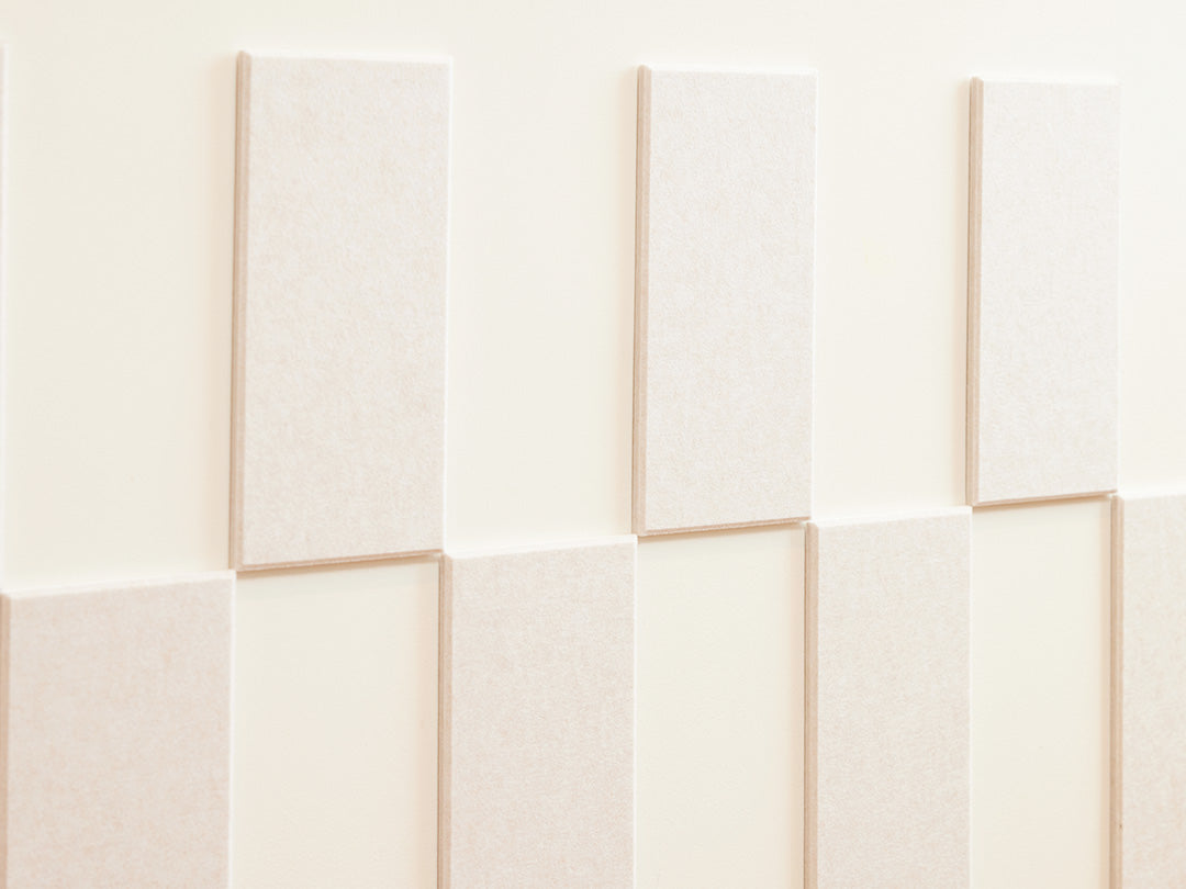 Felt Right wall art design using cream felt tiles and negative space to create a pattern going around the wall and a woman leaning on it