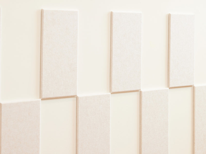 Felt Right wall art design using cream felt tiles and negative space to create a pattern going around the wall and a woman leaning on it