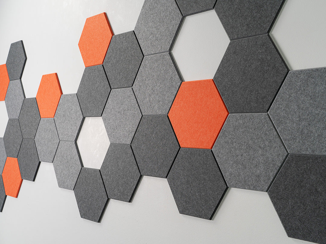 Felt Right wall design using hexigonal designs with pops of orange surrounded by shades of grey felt tiles
