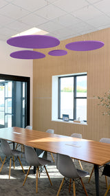 Four purple oval acoustic baffles suspended from ceiling above conference table in office space.