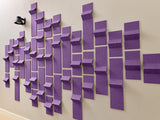 Purple dimensional tiles arranged on a wall in varying heights and depths creating a 3D pattern.