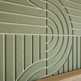 A close-up of a textured olive green wall panel with a raised geometric pattern of concentric arches and vertical lines, with a light wood surface visible at the bottom edge.