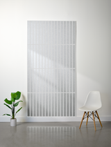 Large white felt sheet with parallel vertical line engravings displayed on wall.