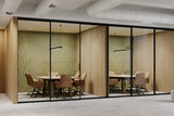 Modern office with glass-walled conference room, olive acoustic panels, and wooden furniture.