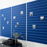 Blue bulletin board in office above black desk.