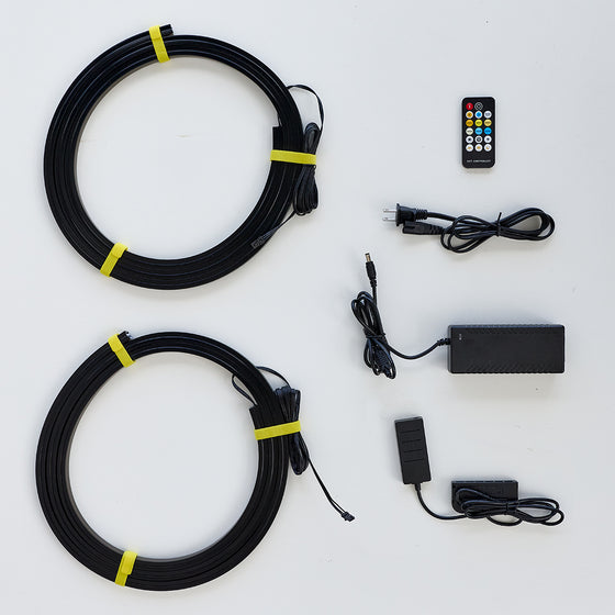 Black coiled cable kit with two large loops secured by yellow bands, shown with a remote control, power adapter, and small push-button controller on a white background.